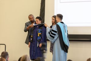 HESA graduate being hooded at 2019 ceremony. [Links to Diversity, Equity, and Inclusion Statement.]