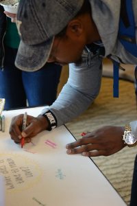 A HESA student writes on a poster at a 2019 gallery walk.